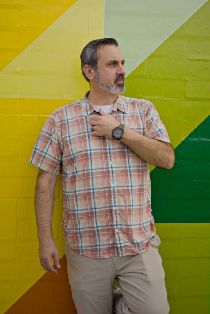 Jason Jurado standing against a colorful painted wall
