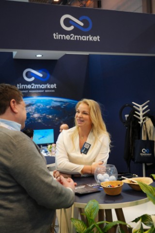Eszter Pontenagel talking with a visitor at the Time2Market stand at a trade fair