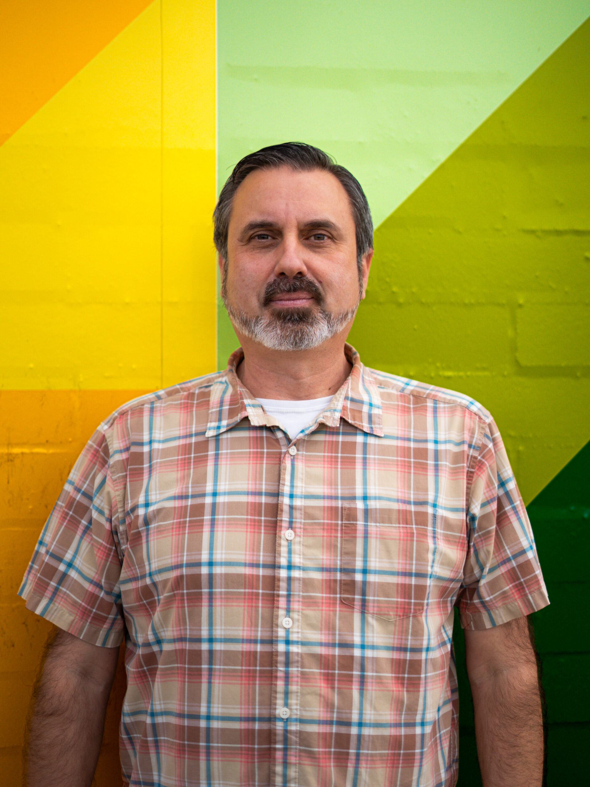 Jason Jurado standing in profile against a colorful painted wall